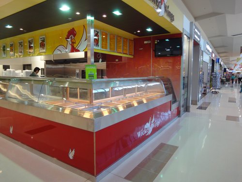 Red-fronted hot food display counter with curved glass in a shopping centre